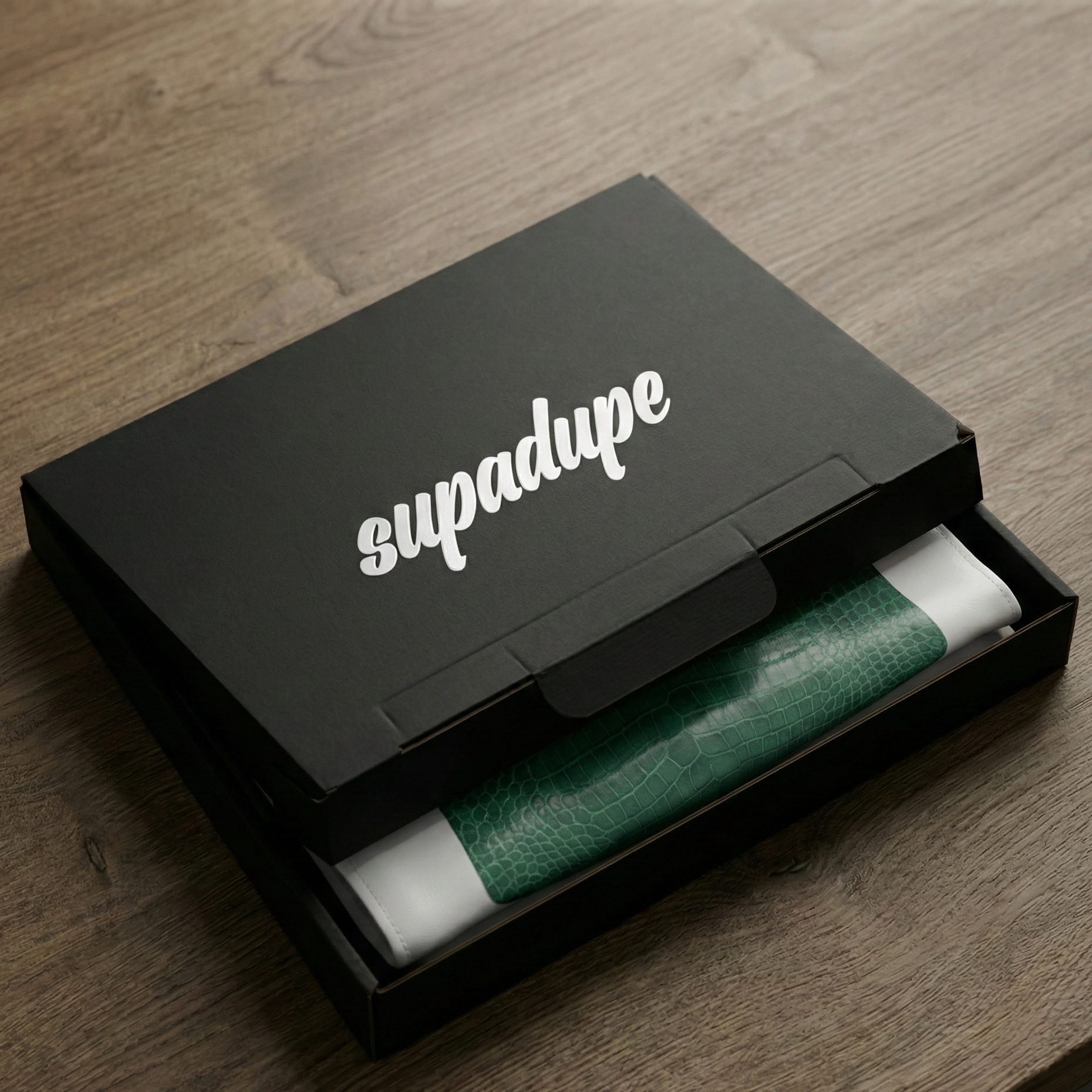 Black box with 'supadupe' branding containing a green and white product on a wooden surface